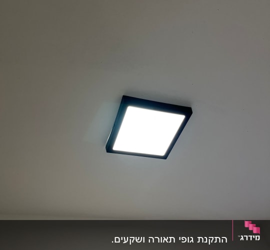 תאורת תקרה מרובעת דולקת על תקרה לבנה